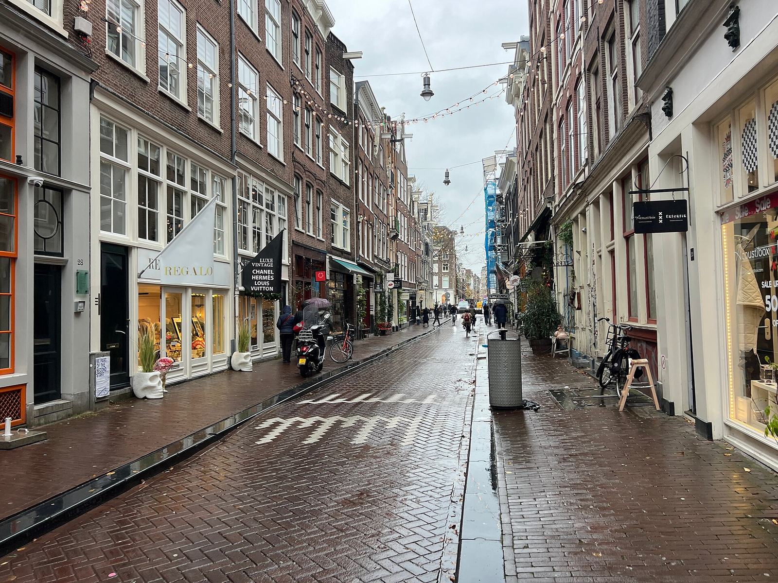 The Reestraat in the Nine Streets on a wet autumn day: shop fronts with awnings, a vintage store and bikes on the brick pavement between tall canal houses