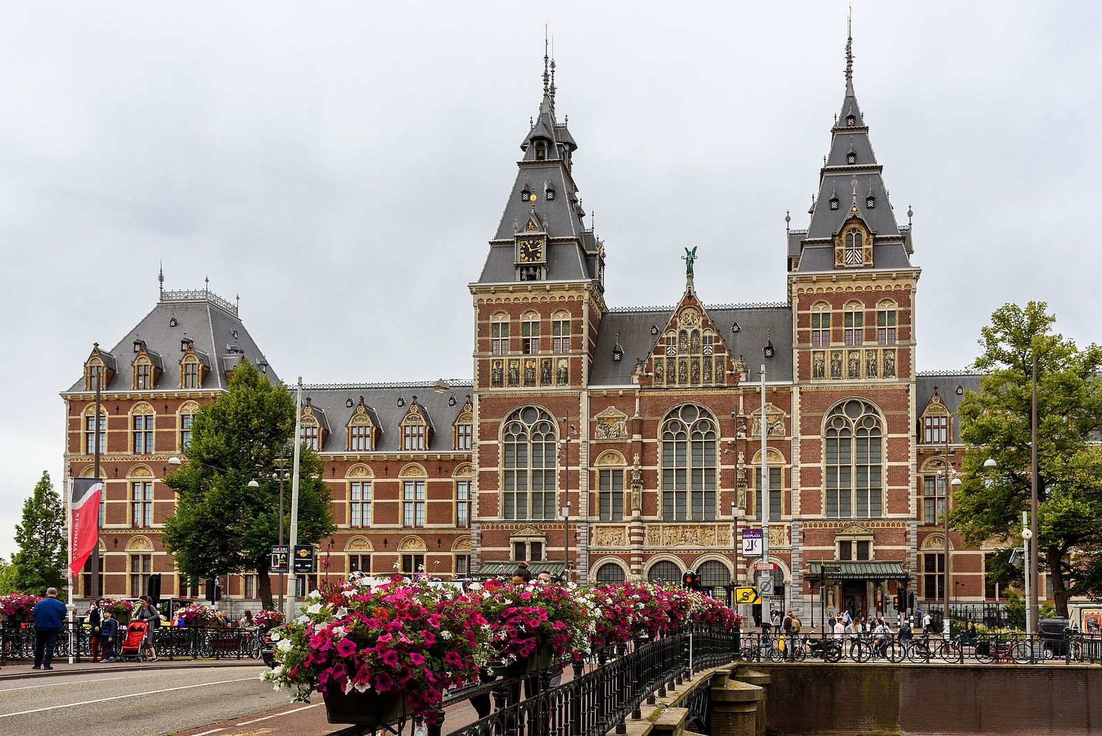 The red-brick Rijksmuseum with its two towers, seen across a bridge lined with pink flower boxes