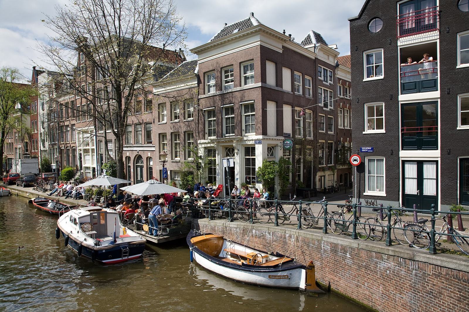 Café 't Smalle on the Egelantiersgracht, with people at tables on its waterside terrace, small boats moored alongside and canal houses behind
