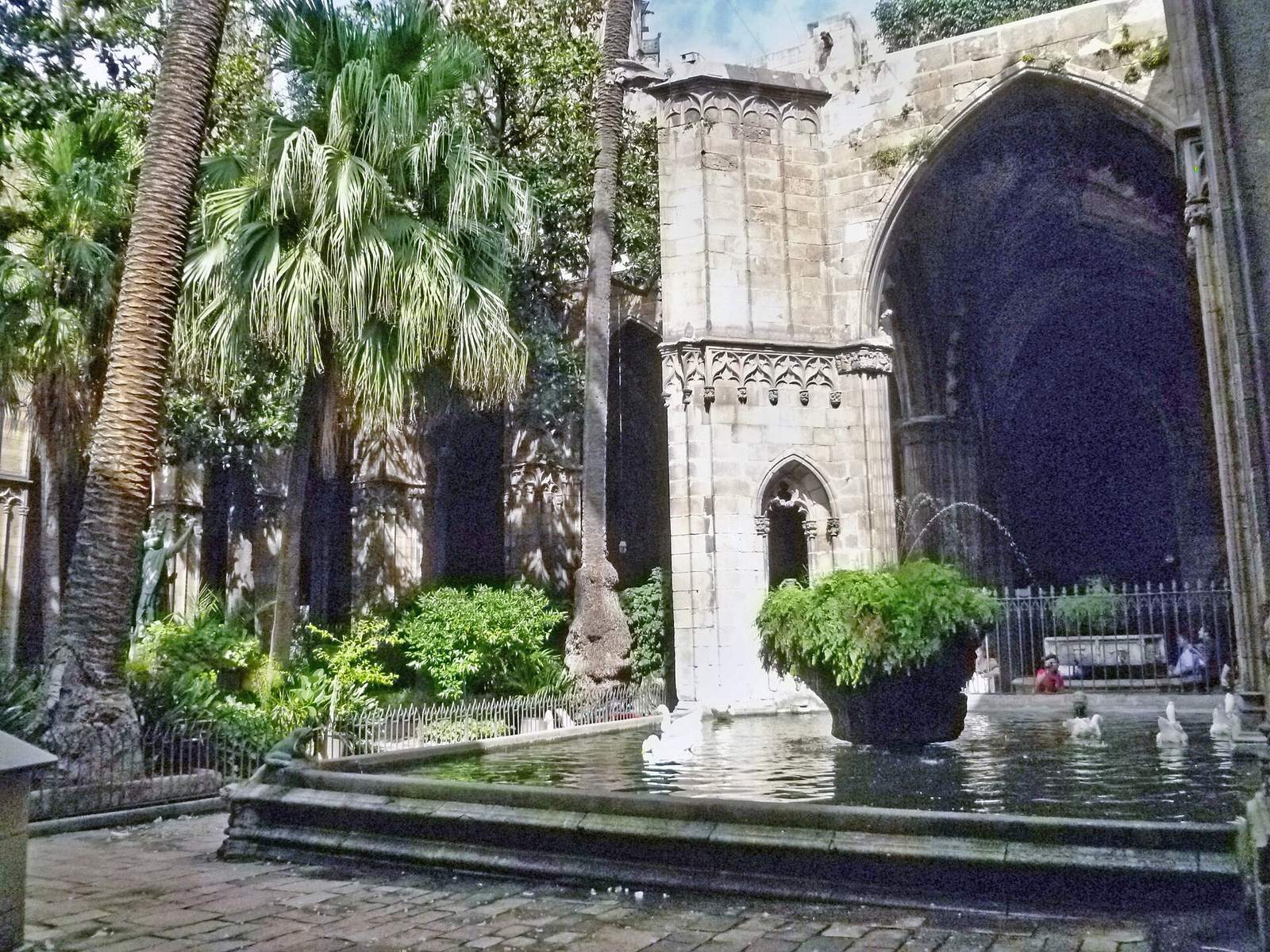 The cathedral cloister: palms and ferns around a Gothic arcade and a stone fountain whose pool is home to white geese