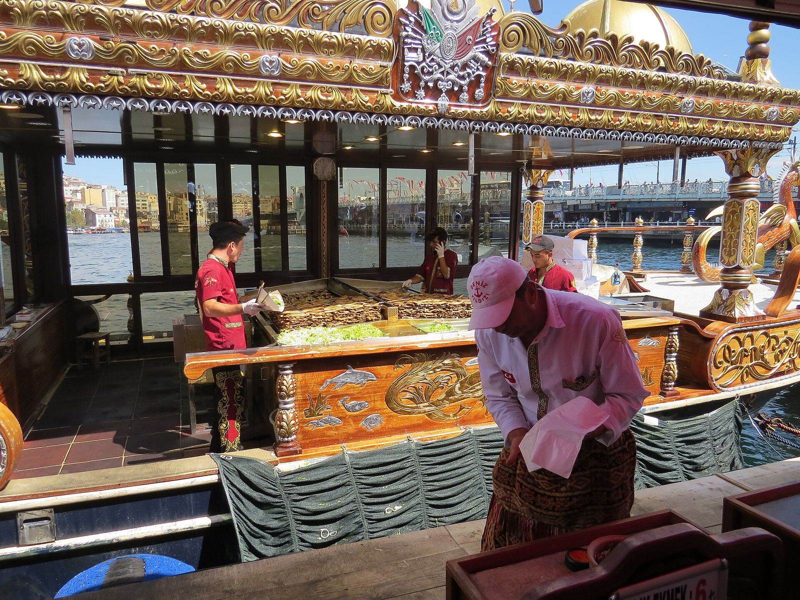 A cook at the grill on an ornate, gilded balık ekmek boat