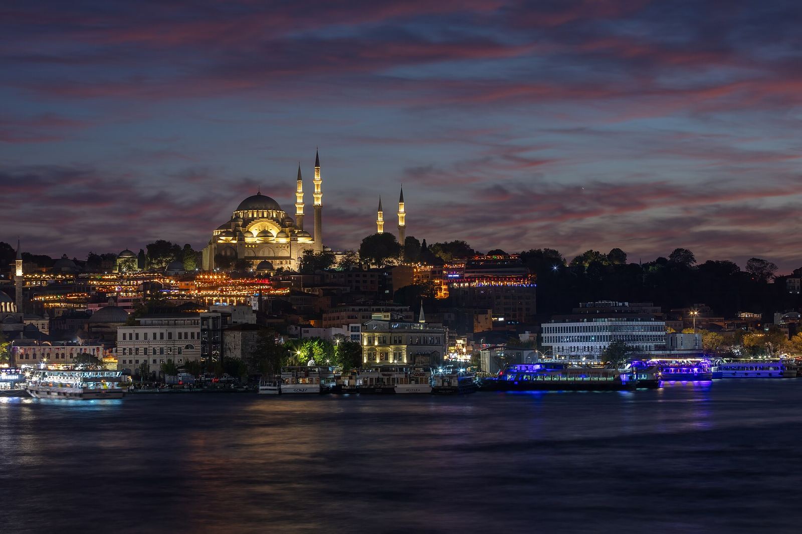 Süleymaniye Mosque lit up on its hill above the Golden Horn at dusk, seen across the water