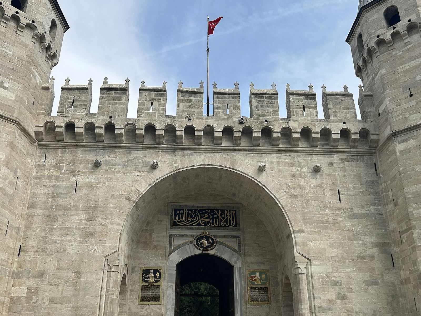 Topkapı Palace's Gate of Salutation, a stone gateway between two pointed towers under a Turkish flag