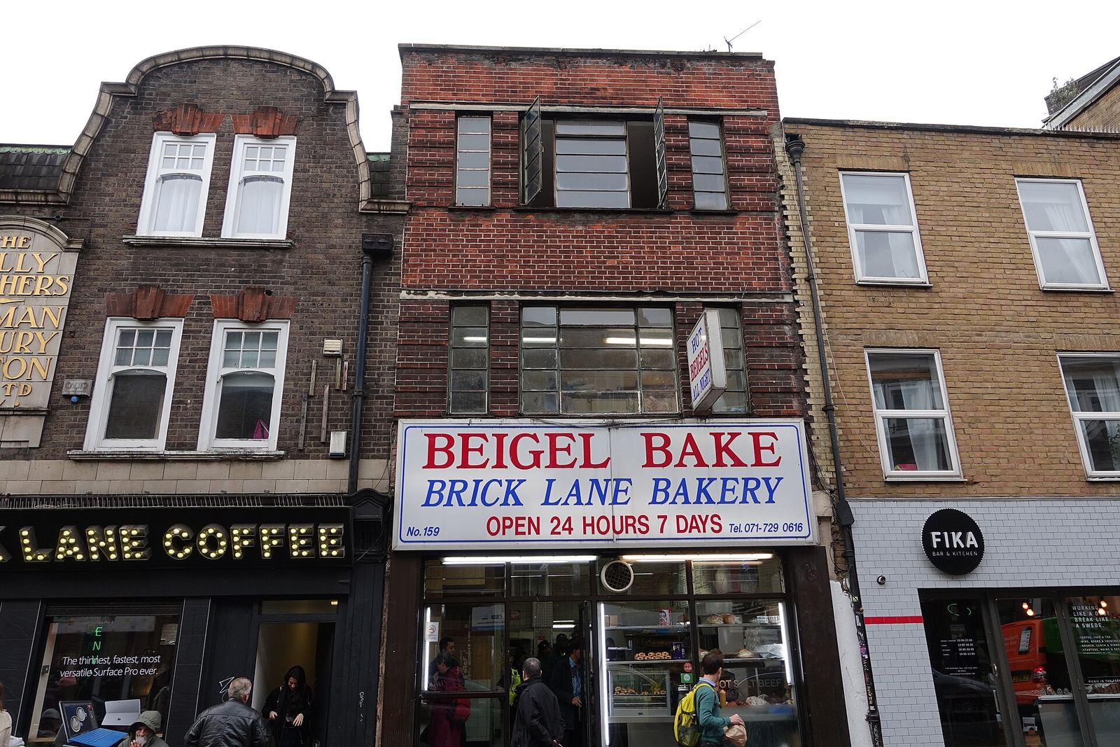 Beigel Bake on Brick Lane: a narrow brick shopfront under a white sign reading BEIGEL BAKE, BRICK LANE BAKERY, OPEN 24 HOURS 7 DAYS