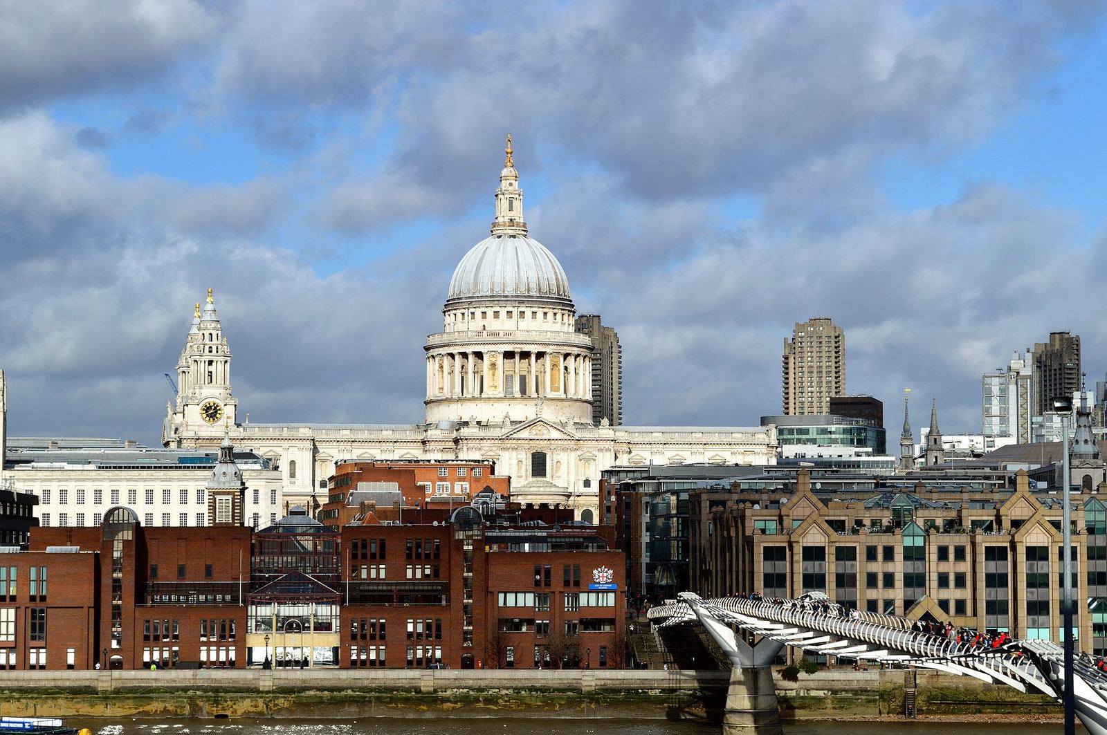St Paul's Cathedral's dome rising above the north bank of the Thames, seen from Tate Modern, with the Millennium Bridge crossing the river in the foreground