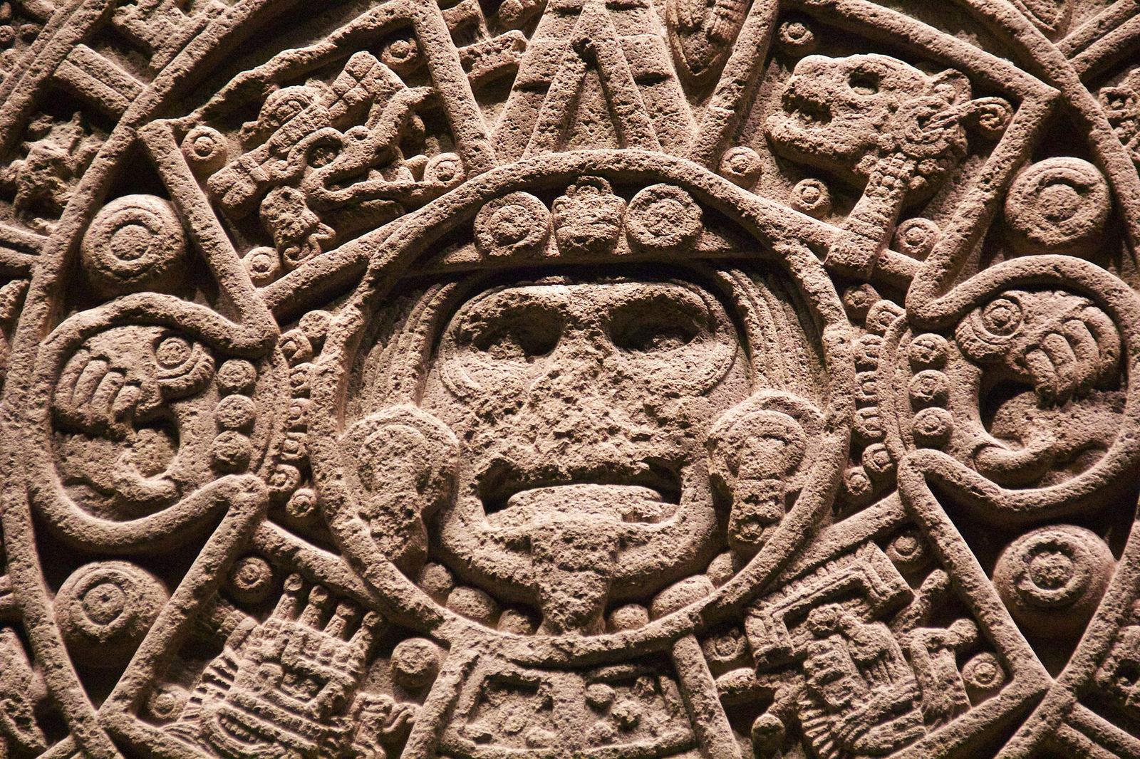 Close-up of the carved face at the center of the Aztec Sun Stone in the Museo Nacional de Antropología, surrounded by rings of glyphs cut into basalt