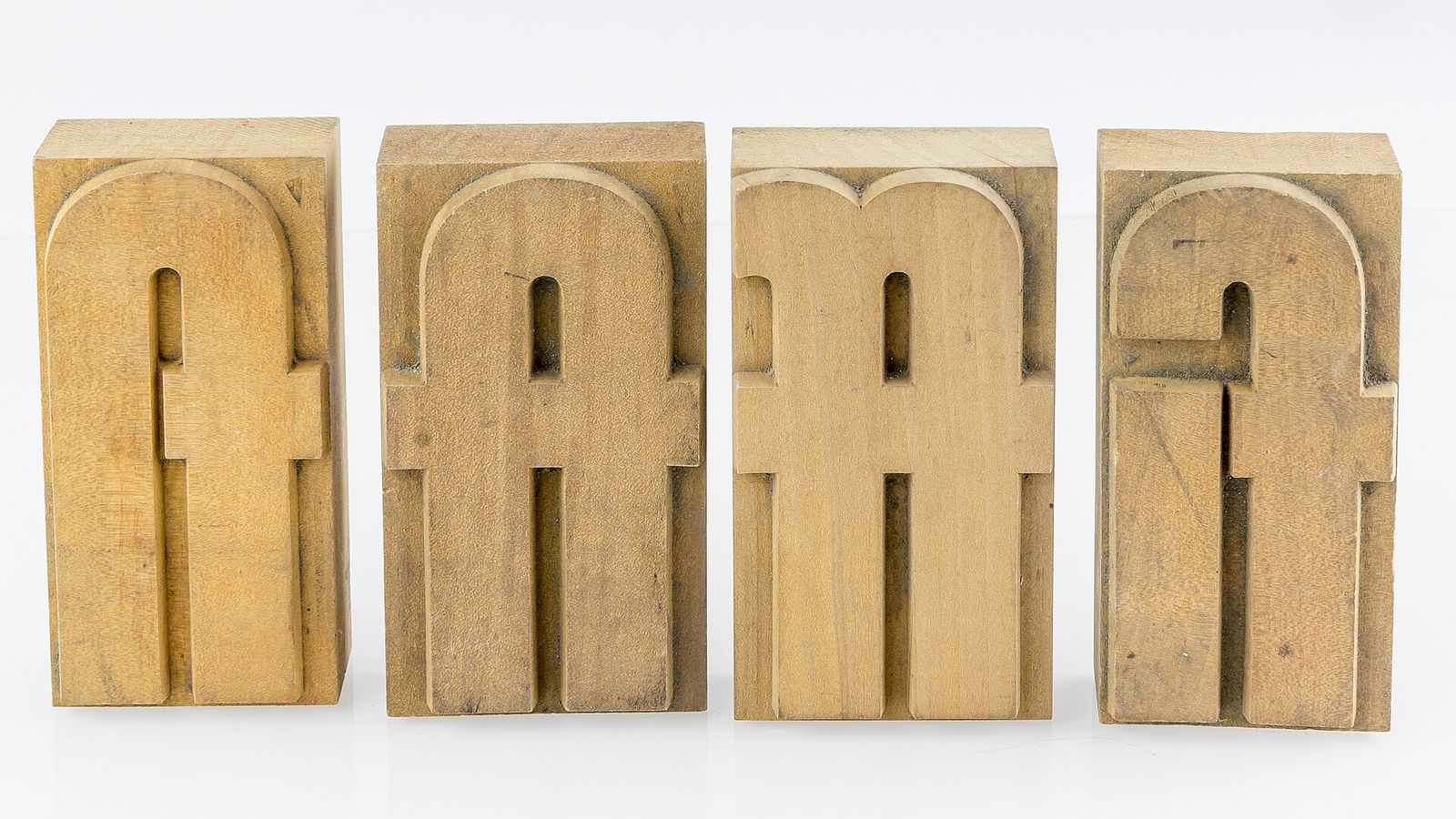 Four wooden type blocks, each carrying two letters cut as one shape: fl, ft, ff and fi, mirror-reversed as all type is
