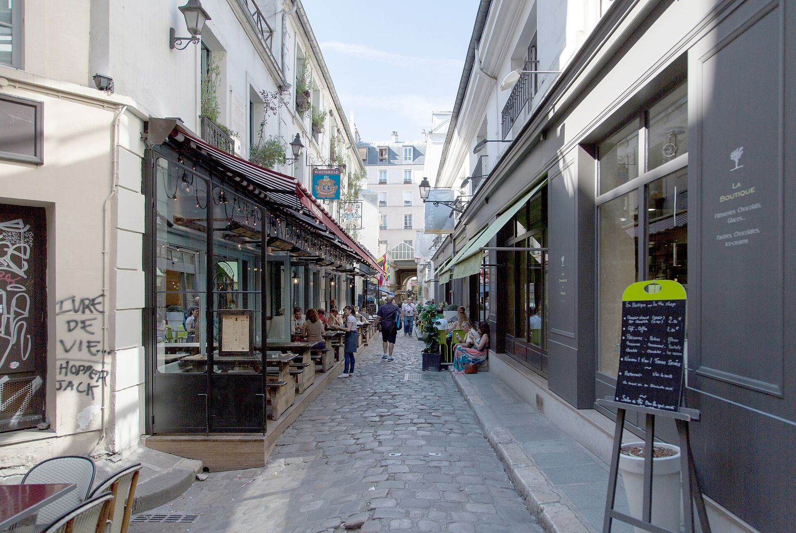 The narrow cobbled Cour du Commerce Saint-André, lined with restaurant terraces, chalkboard menus and old shopfronts