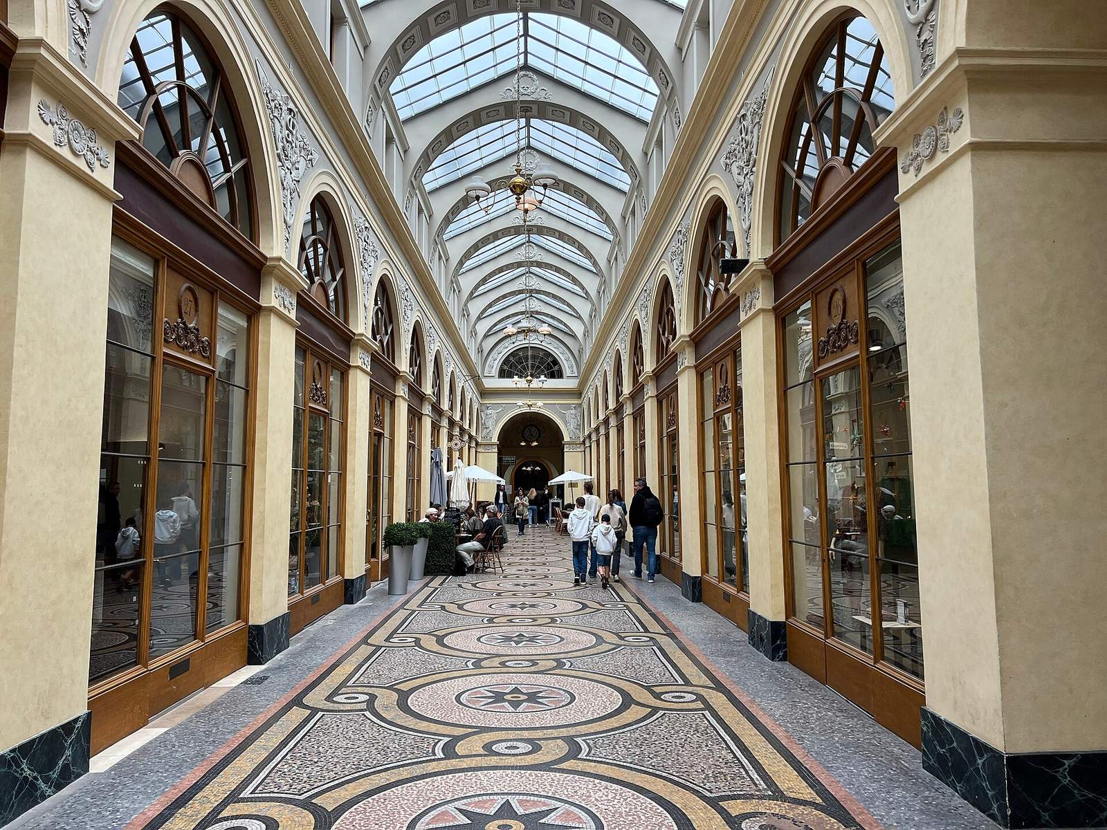 Galerie Vivienne, a covered passage with a glass barrel roof, a mosaic floor patterned with circles and stars, and arched wooden shopfronts