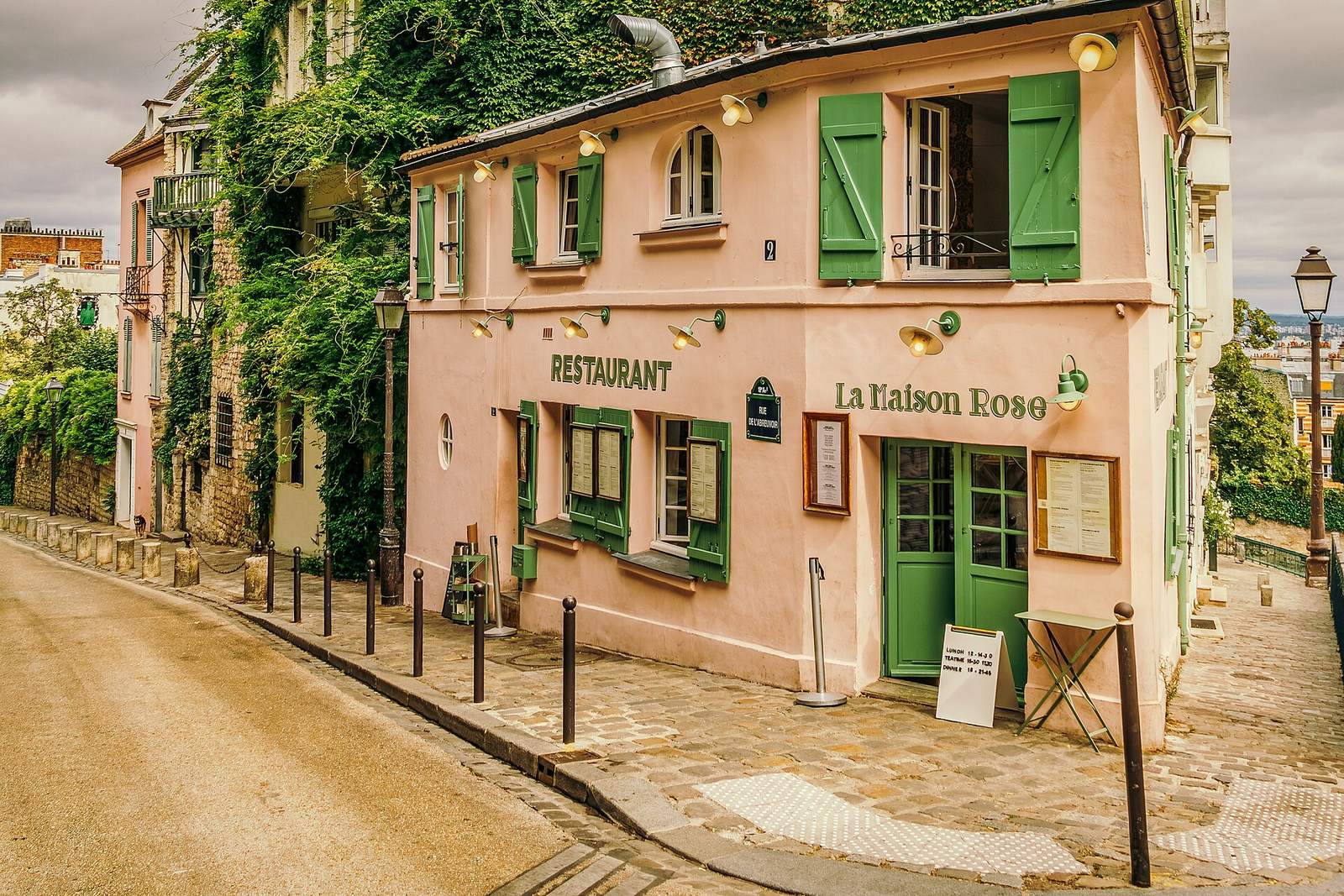 La Maison Rose, a small pink café with green shutters, on the cobbled corner of Rue de l'Abreuvoir in Montmartre