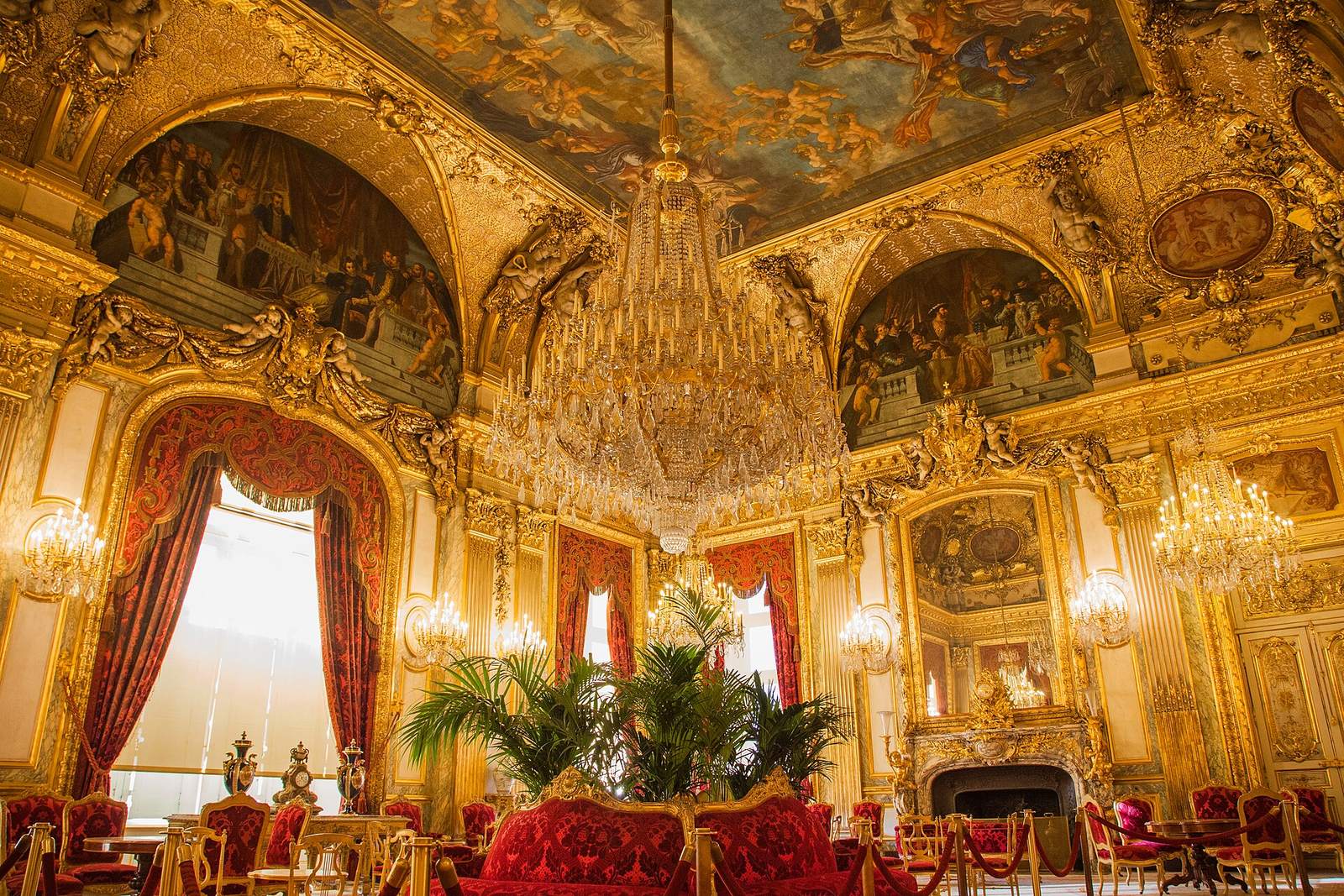 The Grand Salon of the Louvre's Napoleon III Apartments: a huge crystal chandelier, gilded and painted ceilings, red velvet sofas and palm plants