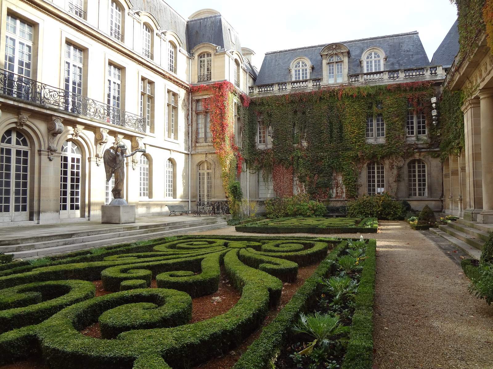 The garden courtyard of the Musée Carnavalet, with scrolling boxwood parterres in front of ivy-covered stone mansion facades