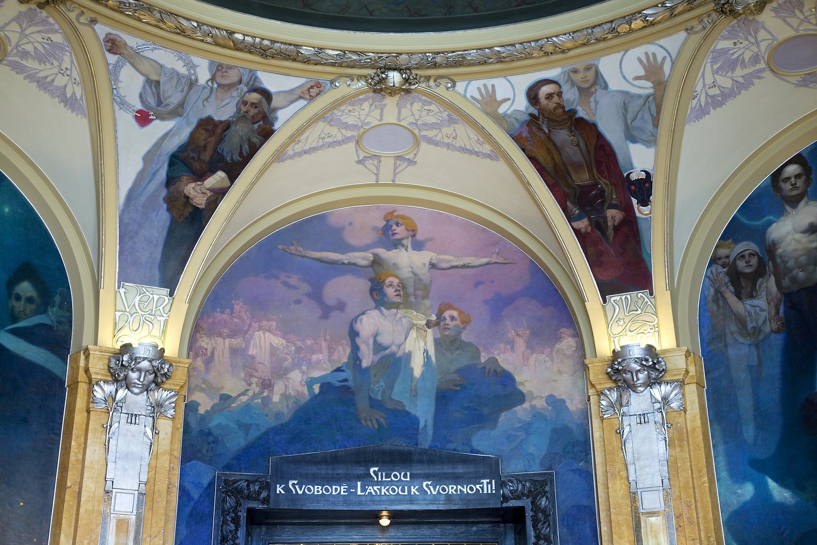 Alfons Mucha's paintings in the Mayor's Hall of the Municipal House: robed figures in the arches above a doorway with a gold inscription