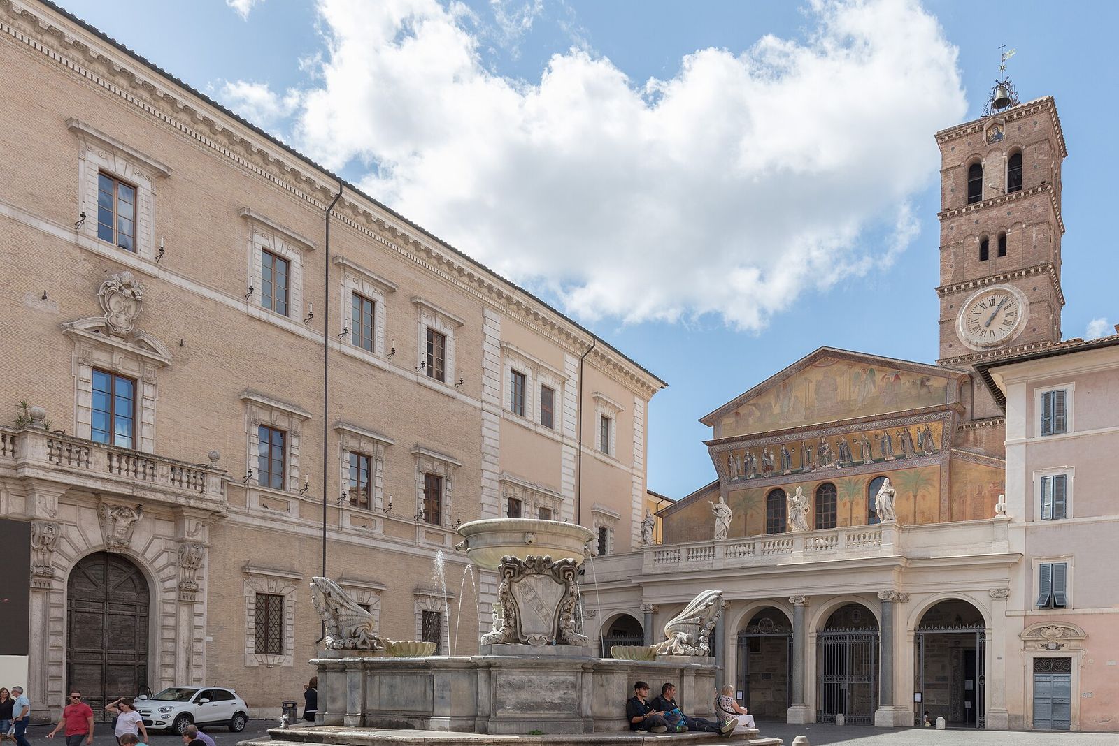 Piazza di Santa Maria in Trastevere: the fountain in the middle with people sitting on its steps, and the basilica's gold mosaic facade and Romanesque bell tower behind