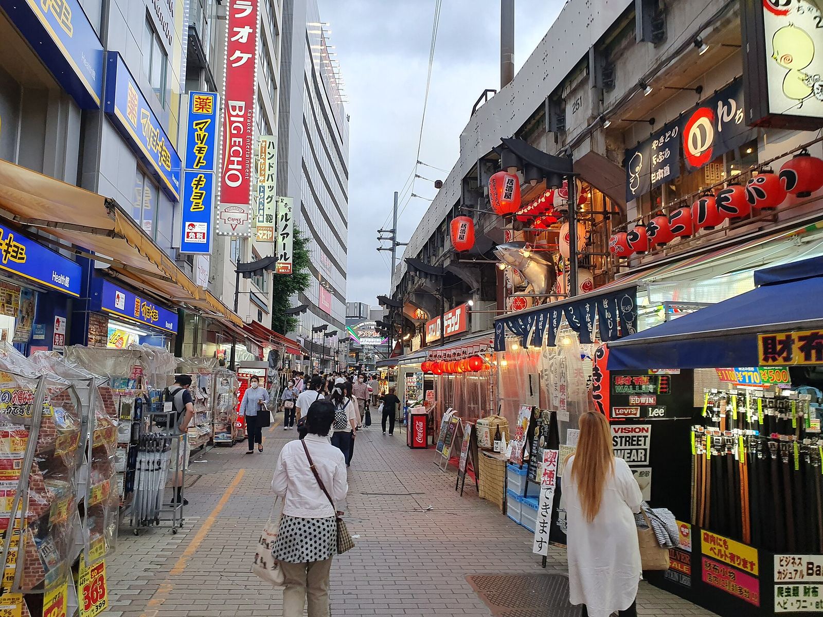 Ameyoko market street in Ueno, with shop signs, red lanterns and stalls on both sides and shoppers walking down the middle