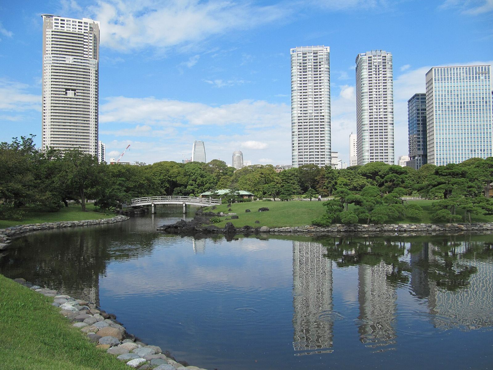 The pond at Hama-rikyu Gardens with the bridge to the Nakajima teahouse in the distance and the Shiodome skyscrapers reflected in the water