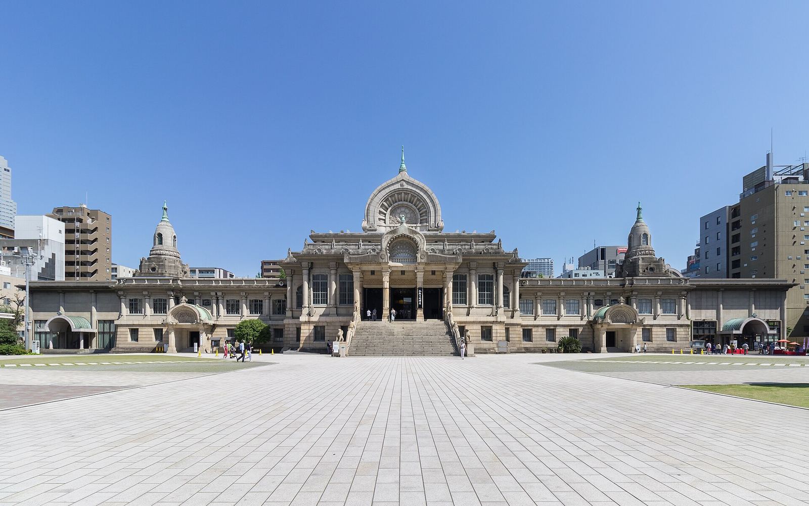 The domed stone main hall of Tsukiji Hongwanji behind its wide paved forecourt under a clear sky